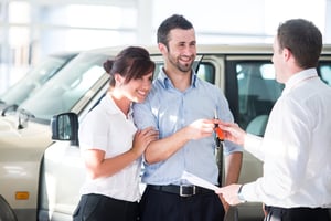 Happy couple getting car keys from a car seller